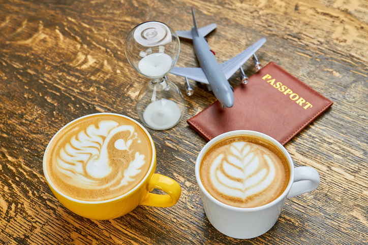 stock image of two cups of coffee an hourglass and a passport