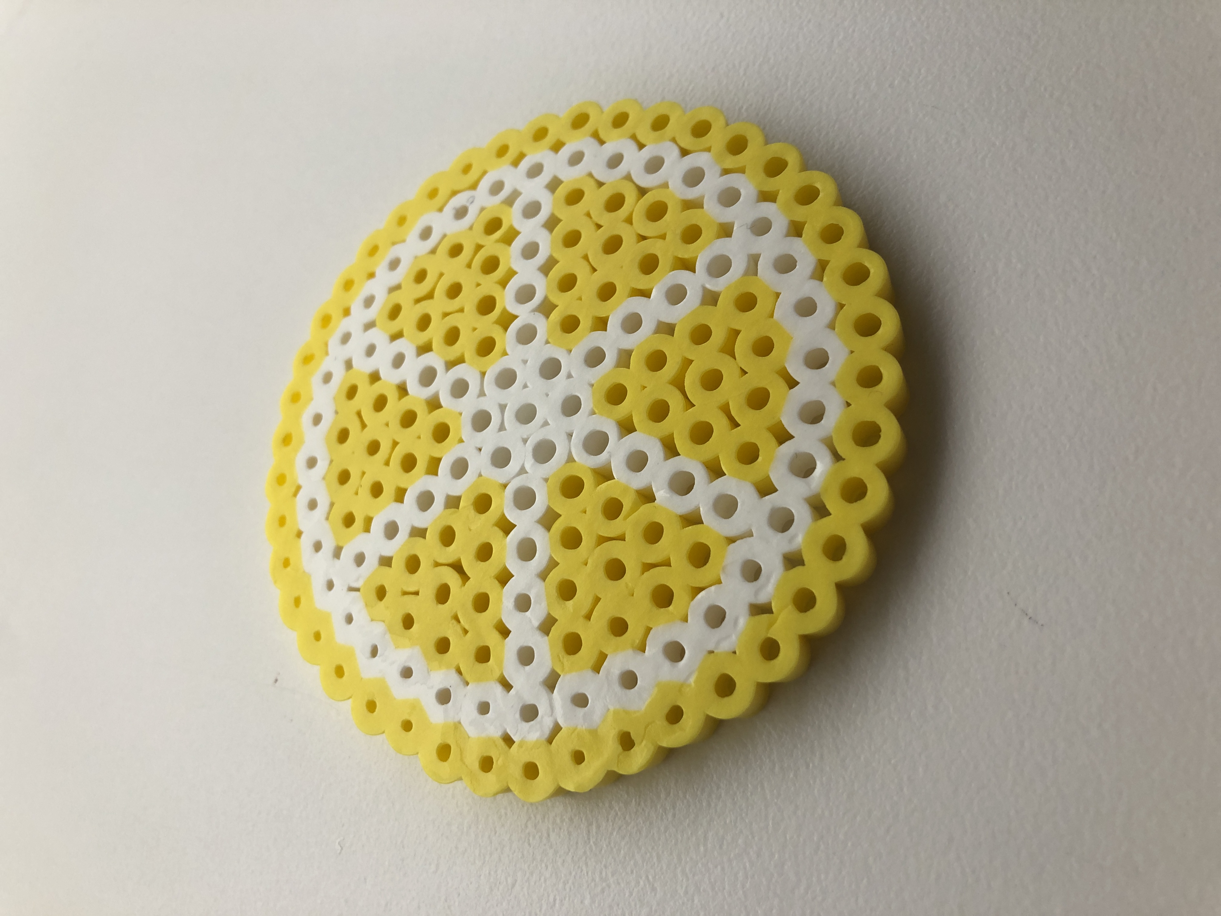 a flat circle made out of beads that looks like a lemon