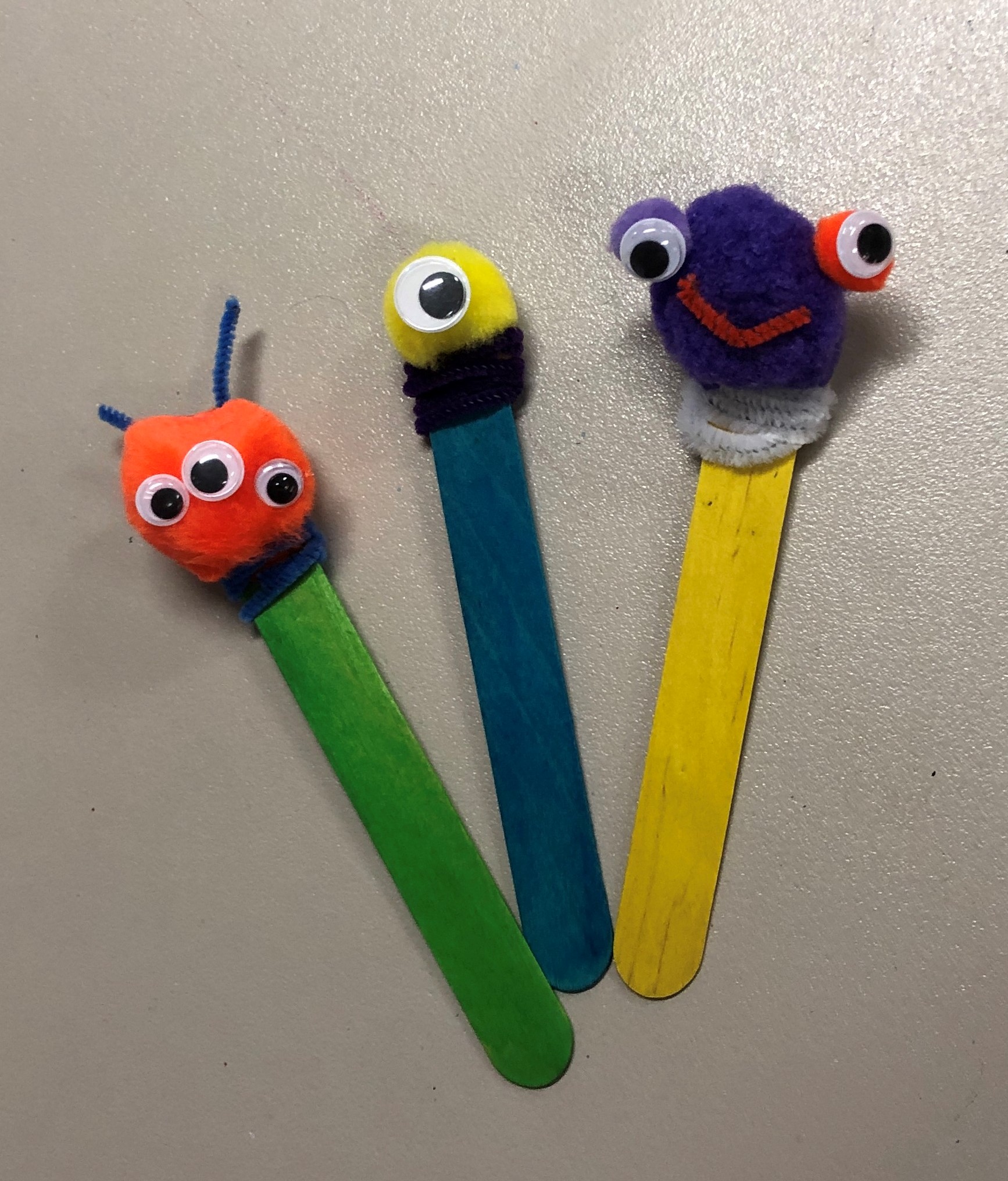 Popsicle sticks with pom-poms, googly eyes, and pipe cleaners