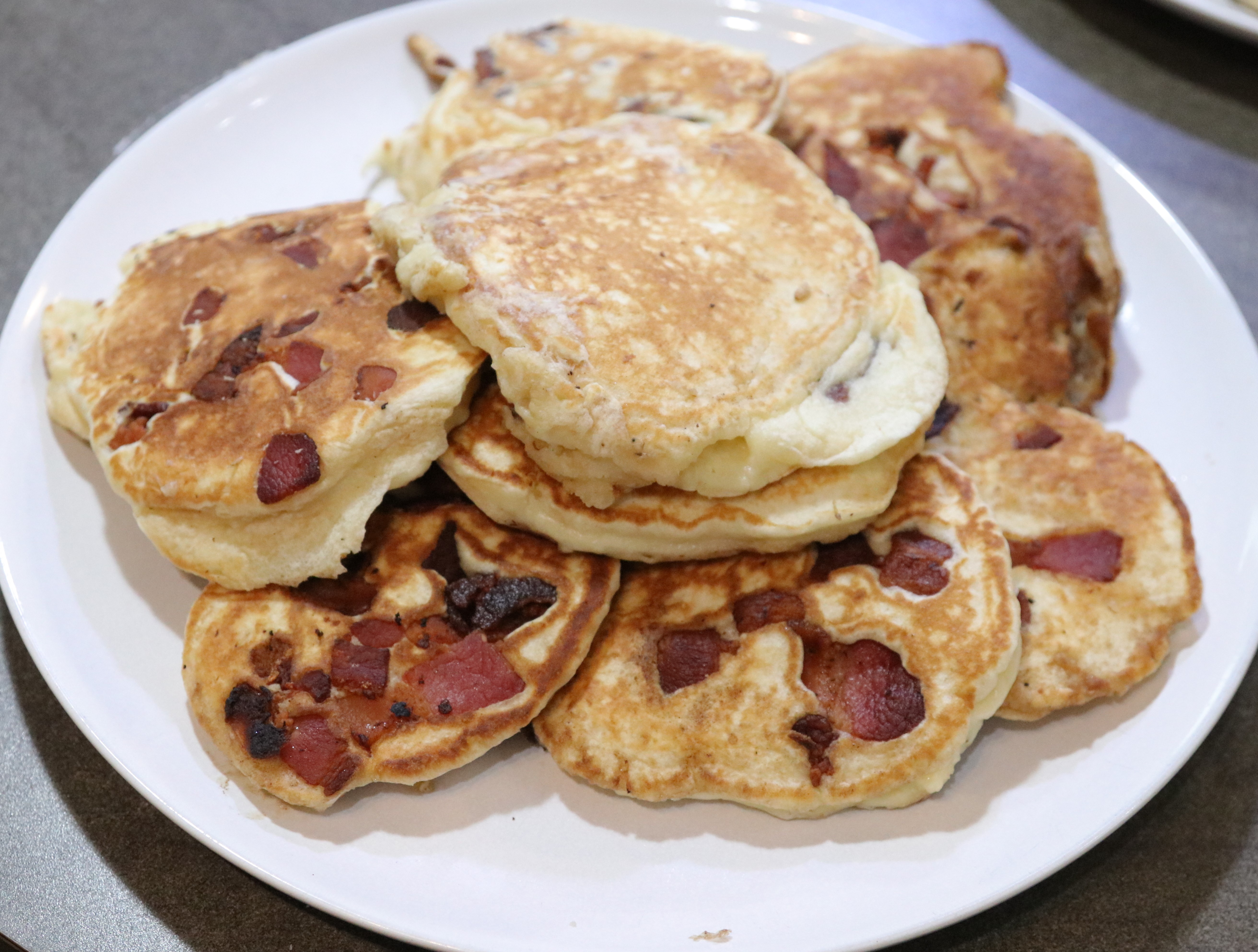 a plate of pancakes with chunks of bacon in them