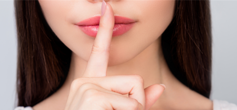 Woman with her finger to her lips to indicate silence 