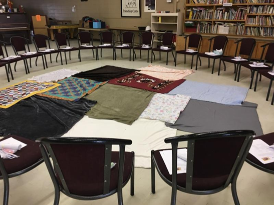 circle of chairs with blankets spread out in the middle 