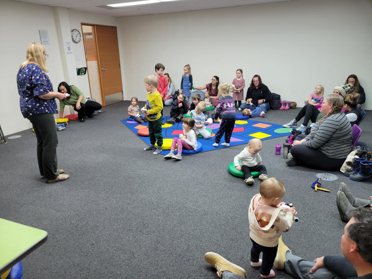 Lori leading a group of young children and their caregivers in song.